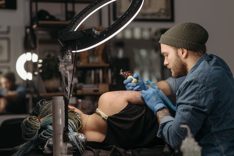 Tattoo artist working on a client’s arm in a studio